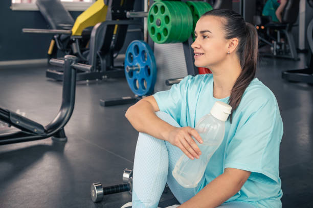 mujer con una botella de agua en el gimnasio después de un entrenamiento. - aerobics beautiful bottle body fotografías e imágenes de stock