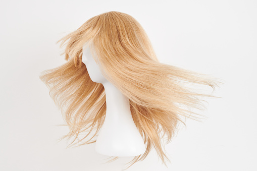 Curly hair wig over the white plastic mannequin head isolated over the white background