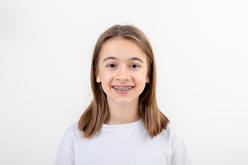 Brunette Caucasian girl smiling with braces on her teeth on a white background isolated, dental health concept.