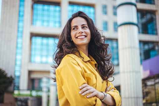 Portrait of young business woman standing outdoors. Close up portrait caucasian young happy woman with fresh and clean skin stands outside. Content gorgeous brunette