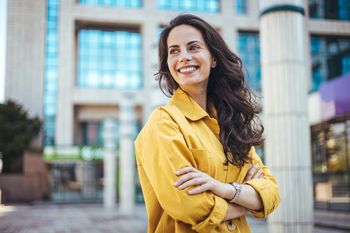 Portrait of a confident young businesswoman standing against an urban background. Portrait of carefree young woman smiling and looking at camera with urban background.