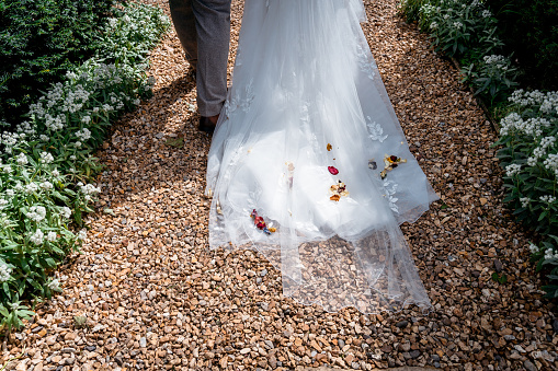 The bride in a beautiful white dress runs to her husband holding a bunch of flowers standing in the park