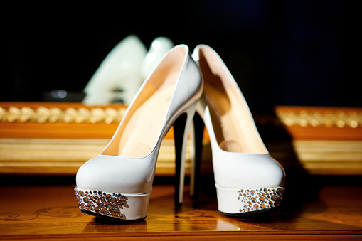 Detail of a bride who after the ceremony changes her elegant high-heeled shoes with comfortable sneakers while sitting on a sidewalk