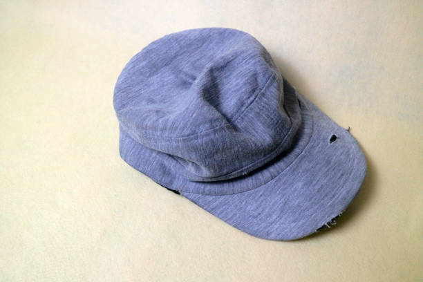 灰色の布製の帽子は擦り切れた状態で、数枚の破れがあります。クリーム色の背景 - baseball isolated ストックフォトと画像