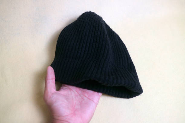 istock A hand holding a Black beanie, made from knitted fabric. on a white or cream background 1816387709