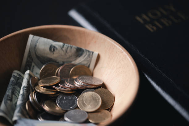 One tenth or tithe is basis on which Bible teaches us to give one tenth of first fruit to God. coins with Holy Bible. Biblical concept of Christian offering, generosity, and giving tithes in church.