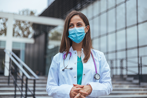 Covid19, coronavirus, healthcare and doctors concept. Portrait of professional confident young doctor in medical mask and white coat, stethoscope over neck, ready help patient, fight disease