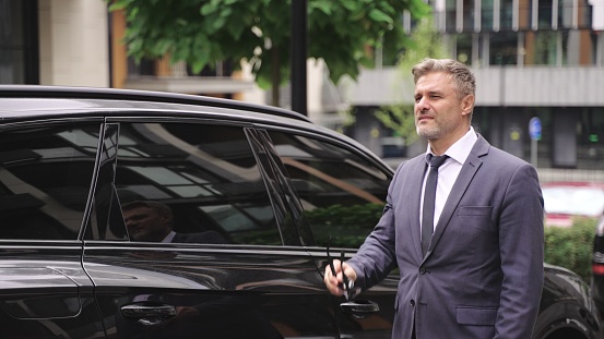 Handsome businessman standing next to his luxury limo