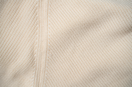 The seam of beige knitted sweater, close-up, full frame fabric background