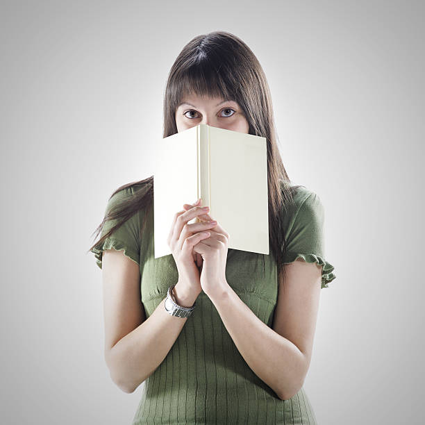 istock woman hides behind a book . cover is blank 181642205