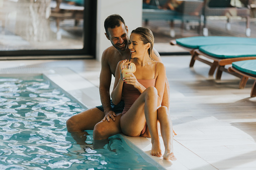 Handsome young couple relaxing by the indoor swimming pool