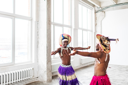Two black dancers in traditional African costumes rehearsing before performance