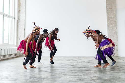 Black male and female dancers dancing in traditional African costumes in dance studio