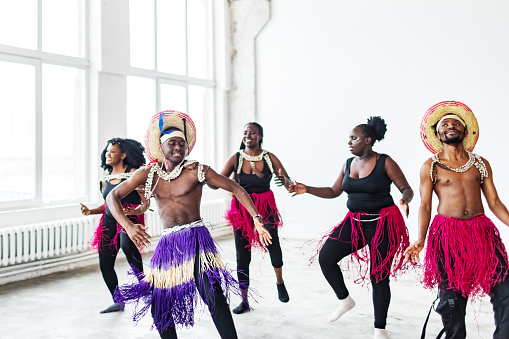 Black male and female dancers dancing in traditional African costumes in dance studio