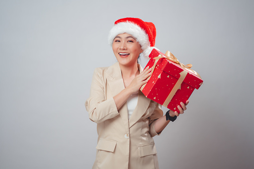 Asian woman wearing Santa hat happy smiling holding gift box standing isolated on white background.