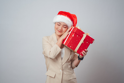 Asian woman wearing Santa hat happy smiling holding gift box standing isolated on white background.