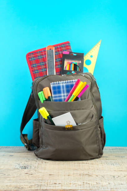 istock Backpack with different colorful stationery on table. Blue background. Back to school. 1816461192