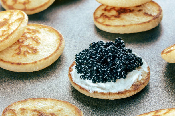 istock Blinis with black caviar and cream cheese, on a festive dish, mini pancakes 1816463380