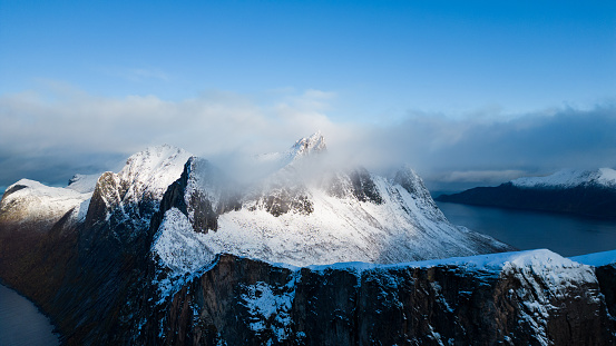 Aerial drone photo of snowy mountain hike up Segla in Senja, Norway.  Snowcapped mountains in the Arctic Circle of Northern Norway.  Famous hike on Senja island.  Shot in October on a DJI Air 2s.
