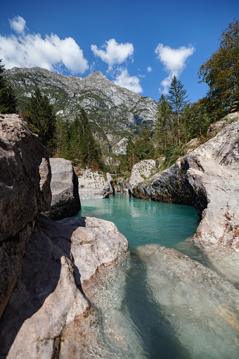 Natural landscape formed of rocks, mountains, trees and a lake with turquoise color in the middle. There is no one and the landscape looks tranquil and beautiful.