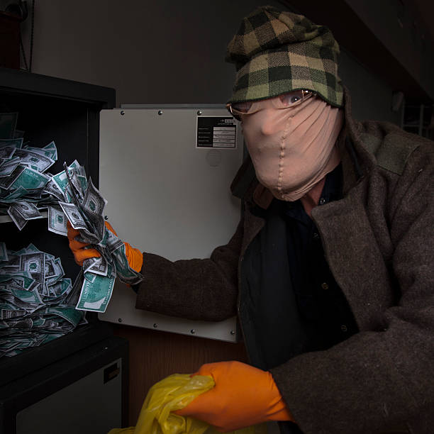 The burglar commits a crime in Luxury apartment with stucco. Thief with black balaclava stealing modern Electronic safe box