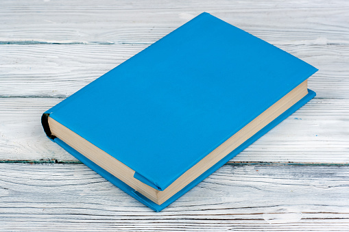 Closed blue book on a white wooden table. Copy space for text
