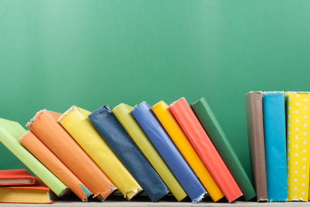 istock Book stacking. Open hardback books on wooden table and green background. Back to school. Copy space for ad text 1816497957