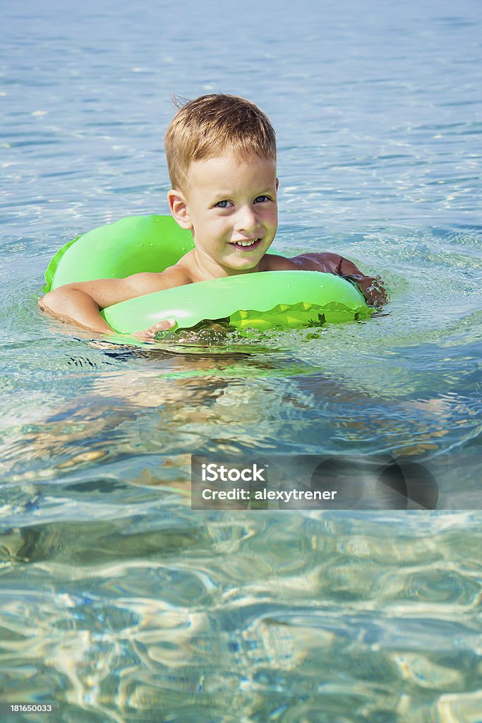 Felice ragazzo godendo di nuoto in mare con anello di gomma - Foto stock royalty-free di Allegro