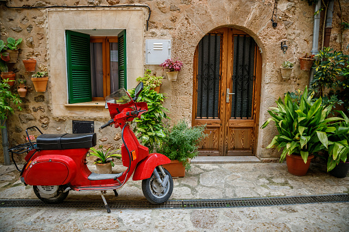 An old red scooter parked near the entrance to an old house in the European old town