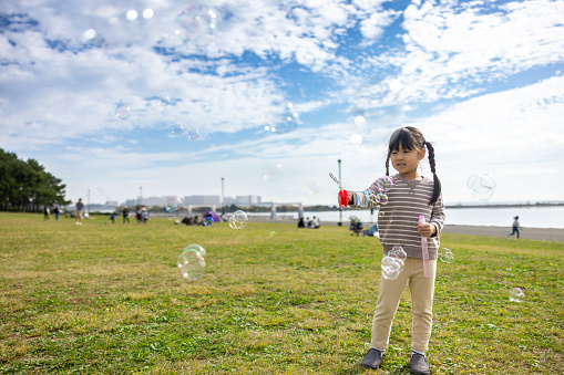 Little girl playing bubbles in public park