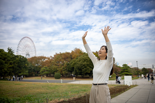 Woman looking up and waving hands in public park