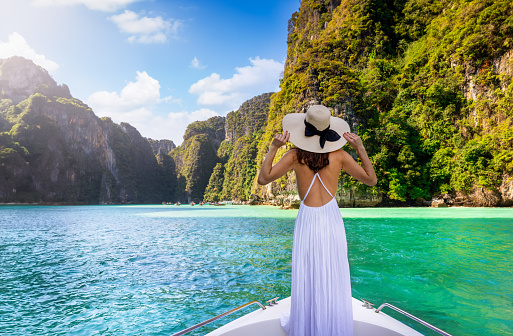 A tourist woman in white summer dress stands on a yacht at the beautiful Phi Phi islands, Tourism Phuket, Krabi, travel concept for Thailand