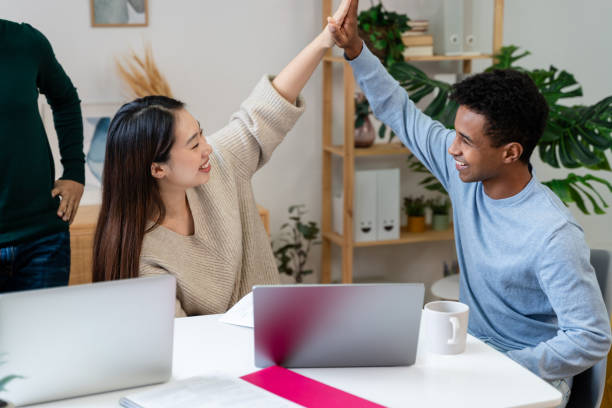 istock cheerful multiethnic colleagues giving high five at workplace in office 1816568847