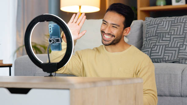 istock Influencer, ring light and smartphone, man wave at camera with social media, live streaming and video while at home. Content creation, communication with followers and tech, happy and subscription 1816574235