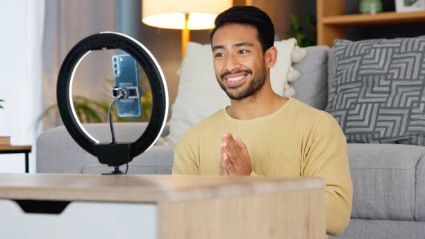 istock Influencer man, phone and ring light for talk, live stream or web chat in home living room. Content creator guy, video call or vlogger on cellphone, contact or recording in lounge, house or apartment 1816574236