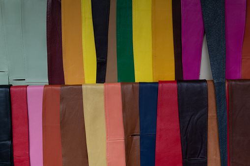 A variety of colorful leather belts and sashes on a display rack in an outdoor market in Florence, Italy.