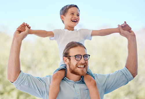 Outdoor, father carrying child and smile with family, adventure and happiness with love, cheerful and support. Face, dad with kid on the shoulders and care in a park, play or relax with joy or nature