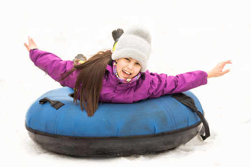 Child riding on tube, little girl during tubing in winter park.