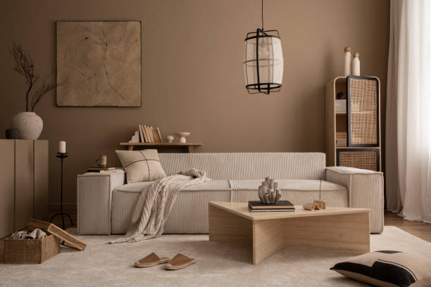 istock Elegant composition of warm living room interior with mock up poster frame, modular sofa, travertine coffee table, gray armchair, rattan sideboard, lamp and personal accessories. Home decor. Template. 1816652638