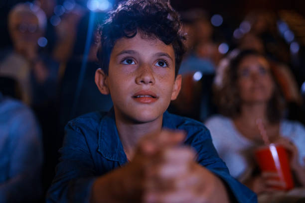 istock Young boy sitting inside movie theater 1816657747