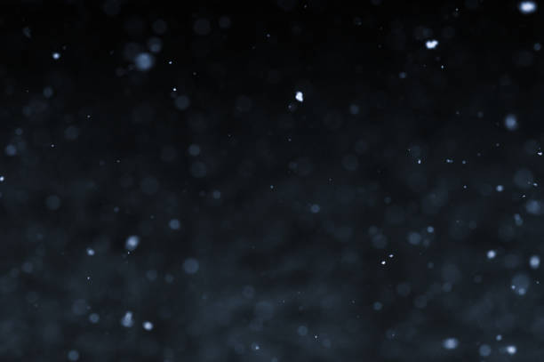 Bokeh of white snow on a black background. Snowfall - new design element.