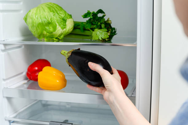 istock A woman puts an eggplant in the refrigerator. 1816684501