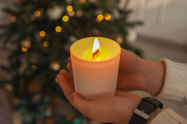 istock Burning candle in hands on a Christmas tree background 1816717308