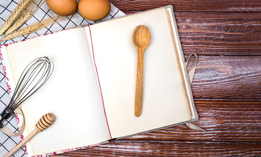 Blank vintage recipe book, eggs and spoon on the wooden background. Top view. Place for text. Banner.