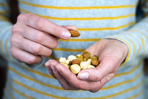 Woman's hands hold a mix of nuts and raisin. Healthy and tasty snack. Close-up. Selective focus.