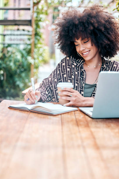 istock Woman, writing and smile in cafe, notebook and planning for future, ideas and vision for growth. Black female person, drinking coffee and laptop for research, restaurant and notes for university 1816745596