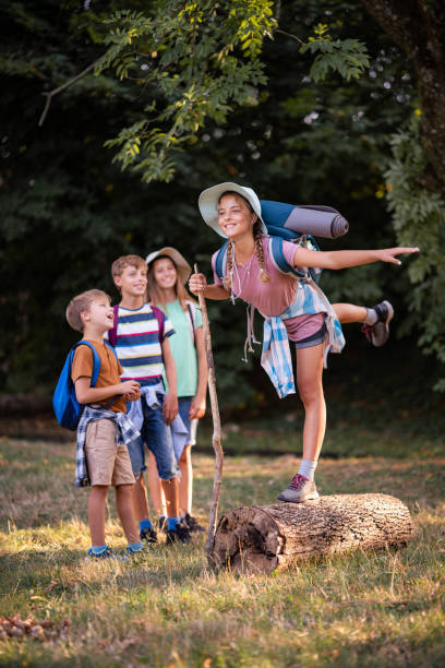 istock Girl whit backpack balancing on tree trunk while her friends standing in background 1816774233