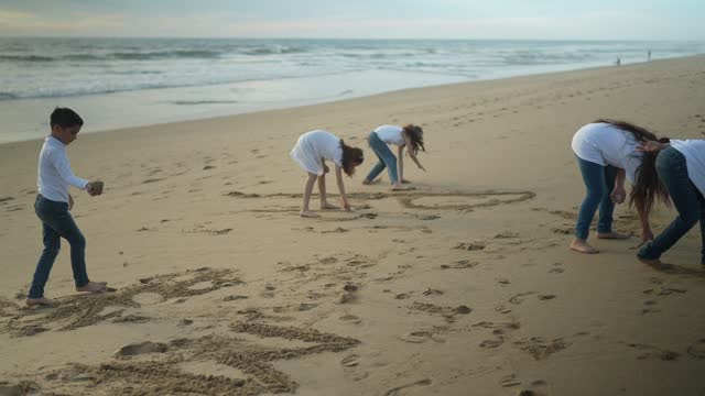 Child friends writing in the sand on the beach