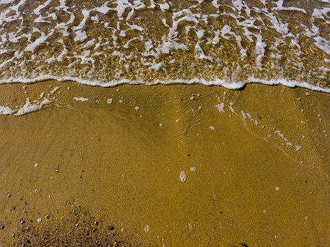 Sea waves coming to an empty beach on a sunny day. No people.