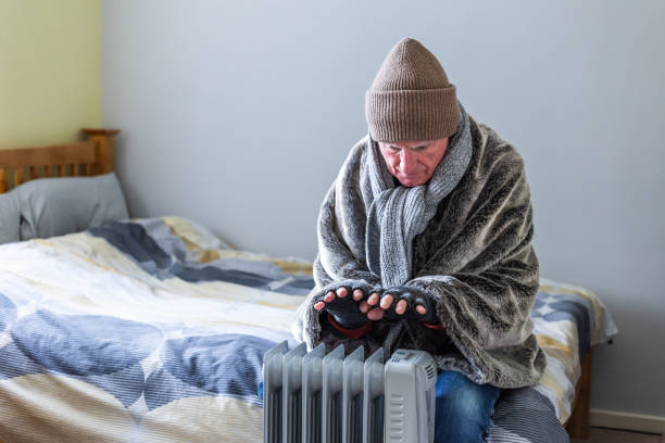 istock Cold senior man warming his hands over electric heater at home 1816805170